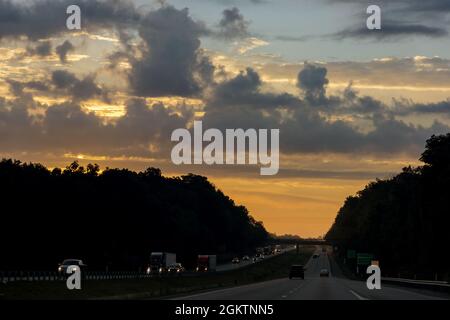 Autos stecken im Verkehr zu dramatischen Sonnenuntergang Zeit Stockfoto
