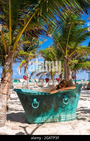 Frau, die sich im Retro-Stil in einer Badewanne aus Metall am Strand entspannen kann Stockfoto