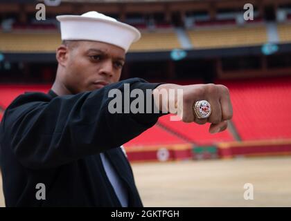 Flugzeugstrukturmechaniker der 3. Klasse Kristopher Williams, der der Zeremonialgarde der US-Marine „Drill Team Platoon“ zugewiesen wurde, posiert für ein Foto mit einem Ring des Kansas City Chiefs Superbowl während einer Führung durch das Feld der Government Employees Health Association im Arrowhead Stadium in Kansas City, Missouri, am 1. Juli 2021. DAS GEHA Field im Arrowhead Stadium ist die Heimat des Kansas City Chiefs NFL-Teams. Die Veranstaltung war Teil der Kansas City Navy Week, der ersten persönlichen Navy Week seit Beginn der COVID-19 Pandemie, die Seeleute verschiedener Navy-Einheiten in den USA dazu brachte, gezielte Kontakte mit Mitgliedern zu führen Stockfoto