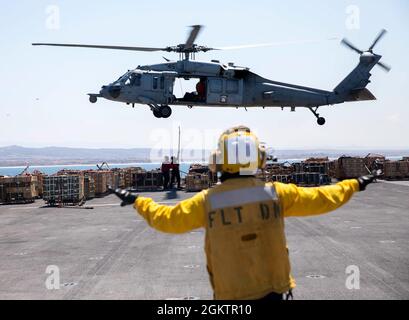 210701-N-GA608-1038 PAZIFISCHER OZEAN (1. Juli 2021) – der Flugflieger der U.S. Navy Aviation Boatswain, Paul Estepa, rechts, leitet einen MH-60S Sea Hawk, der dem Helicopter Sea Combat Squadron (HSC) 23 zugewiesen wurde, während Aviation Ordnanceman Airman Jeremiah Tracy, links, Und Aviation Ordnanceman 3rd Class Aundrey Chandler bringen Ladung bei einer Munitionsentladung an Bord des amphibischen Angriffsschiffs USS Makin Island (LHD 8) an. Makin Island führt Routineoperationen im 3. Flottenbereich der USA durch. Stockfoto