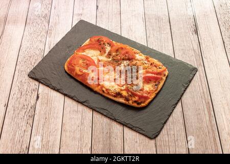 Kleine individuelle Pizza mit Mozzarella, viel Tomaten und Gewürzen nach italienischem Rezept Stockfoto
