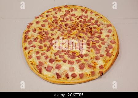 Super york Schinkenpizza schneiden und auf geschmolzenem Mozzarella-Käse auf weißem Karton verteilen Stockfoto