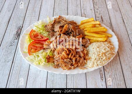 Kebab-Menü Tablett mit gemischtem Fleisch mit Lamm und gehacktem Huhn mit einer Garnierung von Pommes frites und weißem Reis und Eisberg-Hülsenfrüchte-Salat mit Tomaten Stockfoto