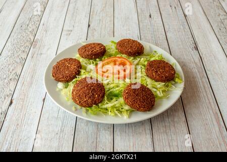 Falafel-Hackbraten auf Eisbergsalat auf weißem Teller, serviert in einem Kebab-Restaurant Stockfoto