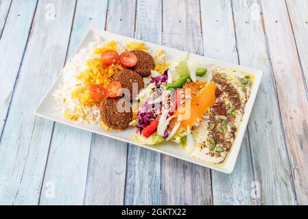 Falafel-Menü mit Joghurt, Kirschtomaten, weißem Reis und Basmati, gemischt mit purpurem Kohl, roten und grünen Paprika, Zwiebeln und Karotten mit Kürbis Stockfoto