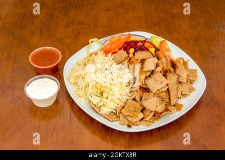 Lammkebab-Menügericht mit Basmati-Reis mit geschnittenem Lammfleisch mit Rüben, Karotten, Gurken und roten Zwiebeln mit Joghurtsauce und würziger Tomatensauce Stockfoto