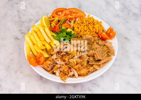 Gemischter Kebab-Teller mit gebratenem Hähnchen- und Lammfleisch, gebratenen Kartoffeln, Bulgur-Eintopf mit Gemüse und Zitrone Stockfoto