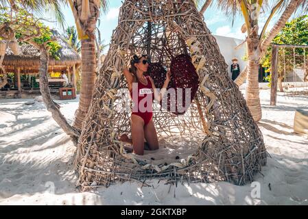 Frau im Badeanzug kniet im Korbzelt im wunderschönen Strandresort Stockfoto