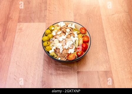 Schüssel Nudelsalat mit frischem Käse, Kirschtomaten, grünen entkernten Oliven und Thunfischkonserven. Stockfoto