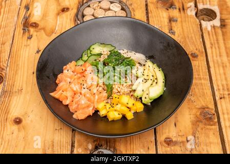 Lachs-Poke-Schale in schwarzer Schale auf Holztisch Stockfoto