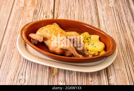 Gebratenes Picanton-Huhn mit gebackenen Kartoffeln in Tontopf zum Einlegen in den Ofen auf den Holztisch Stockfoto