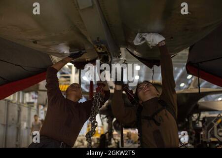 210703-N-XZ686-1050 PAZIFISCHER OZEAN (3. Juli 2021) Flugstrukturmechaniker/in-Lehrling Nicole Chavez (links), aus El Monte, Kalifornien, Und die Flugbaumechanikerin Angelica Kelley aus Amarillo, Texas, waschen das Äußere einer F/A-18F Super Hornet, die den „Black Aces“ von Strike Fighter Squadron (VFA) 41 an Bord des Flugzeugträgers USS Abraham Lincoln (CVN 72) zugewiesen wurde. Abraham Lincoln führt derzeit Routineoperationen im Bereich der 3. Flotte der USA durch. Stockfoto