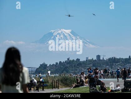 Die Bewohner von Tacoma sehen sich an, wie ein P-40 Warhawk für die Tacoma Freedom Fair fliegt, während ein C-17 Globemaster III von der Joint Base Lewis-McChord in der Nähe von Mount Rainier, Commencement Bay, Washington, 4. Juli 2021 hält. Die Tacoma Freedom Fair wurde von dem F-35A Lightning II Demonstrationsteam der Luftwaffe ausgerichtet und fand in Verbindung mit der Gig Harbor Wings-and-Wheels Air Show 2021 statt. Stockfoto