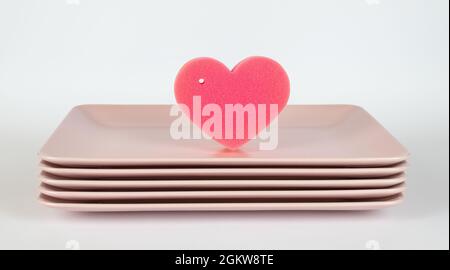 Rosa Teller und ein rosa Küchenschwamm in Herzform Stockfoto