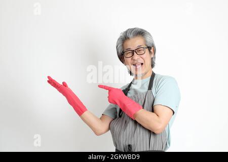 Die ältere asiatische Haushälterin, die auf weißem Hintergrund steht. Stockfoto