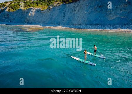 28.Mai 2021. Anapa, Russland. Ein paar Sportler reisen auf dem Stand Up Paddle Board an einem ruhigen Meer. Menschen, die auf Red Paddle im Meer herumlaufen. Antenne Stockfoto