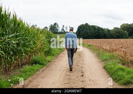 Asse, Flämisch-Brabant - Belgien - 09 12 2021: Mann auf einem weichen Weg zwischen grünen Feldern Stockfoto