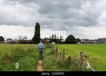 Asse, Flämisch-Brabant - Belgien - 09 12 2021: Mann auf einem weichen Weg zwischen grünen Feldern Stockfoto