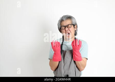 Die ältere asiatische Haushälterin, die auf weißem Hintergrund steht. Stockfoto