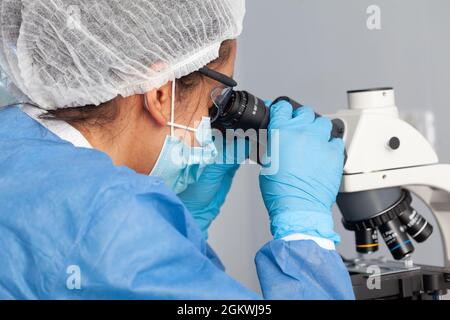 Junge Wissenschaftlerin, die Proben unter dem Mikroskop betrachtet Stockfoto