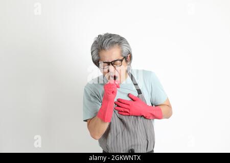 Die ältere asiatische Haushälterin, die auf weißem Hintergrund steht. Stockfoto