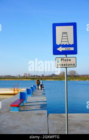 POZNAN, POLEN - 01. Apr 2016: Eine vertikale Aufnahme eines Hinweisschildes an einer Plattform mit einem Paar, das am Malta-See spazieren geht Stockfoto