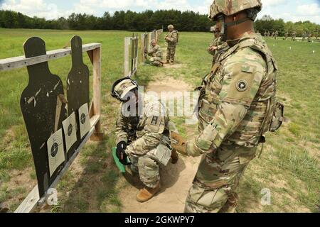 Personal Sgt. Christopher Smith, ein Beobachter/Trainer der US-Armee bei der 181. Multi-Functional Training Brigade, unterstützt Sgt. Jean Sencion, ein Kraftfahrzeugbetreiber bei der 645. Inland Cargo Transportation Company, während der Einzelwaffenqualifikation in Fort McCoy, Wis., 13. Juli 2021. OC/TS helfen bei der Ausbildung und Vorbereitung von Soldaten aus allen Teilen der USA vor dem Einsatz. Stockfoto