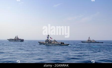 210712-N-JW440-1032 GOLF VON ADEN (12. Juli 2021) – Amphibienschiff USS Iwo Jima (LHD 7), links, Lenkraketen-Zerstörer USS Halsey (DDG 97) und USS the Sullivans (DDG 68) operieren in Formation im Golf von Aden, 12. Juli. Iwo Jima, Halsey und die Sullivans werden in das Einsatzgebiet der 5. US-Flotte eingesetzt, um Marineinteroperationen zu unterstützen, um die maritime Stabilität und Sicherheit in der Zentralregion zu gewährleisten und das Mittelmeer und den Pazifik durch den westlichen Indischen Ozean und drei strategische Engpässe zu verbinden. Stockfoto