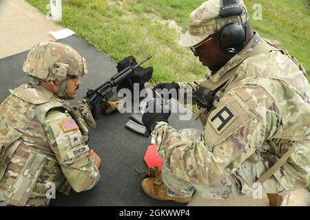 Personal Sgt. Christopher Smith, ein Beobachter/Trainer der US-Armee bei der 181. Multi-Functional Training Brigade, unterstützt Sgt. Jean Sencion, ein Kraftfahrzeugbetreiber bei der 645. Inland Cargo Transportation Company, während der Einzelwaffenqualifikation in Fort McCoy, Wis., 13. Juli 2021. OC/TS helfen bei der Ausbildung und Vorbereitung von Soldaten aus allen Teilen der USA vor dem Einsatz. Stockfoto