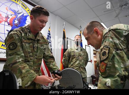 Kaden Norwood, Senior Airman der US Air Force, 1. Wartungstechniker für Kabel- und Antennentheater, zeigt Col. Bryan Callahan, 435. Kommandant des Air Ground Operations Wings, wie eine Drahtprüfmaschine auf dem Luftwaffenstützpunkt Ramstein, Deutschland, 13. Juli 2021 funktioniert. Der erste CMXS ist dafür verantwortlich, dass seine Kunden mit einer Netzwerk- und Kabelinfrastruktur unterstützt werden, damit sie ihre Aufgaben erledigen können, ohne sich Sorgen über die herabgesetzten Kommunikationsfunktionen machen zu müssen. Stockfoto