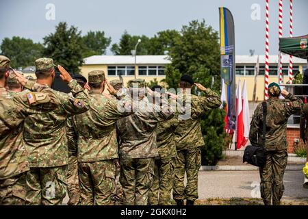 Eine multinationale Gruppe, bestehend aus US-Armee, rumänischen Landstreitkräften und Soldaten der kroatischen Landstreitkräfte, grüßt die polnische Flagge während des 27. Jahrestages der 15. Mechanisierten Brigade in Gizycko, Polen, am 15. Juli 2021. Als eine der Schwestereinheiten der Battle Group Polens innerhalb der multinationalen Division Nord-Osten ermöglicht die 15. Mechanisierte Brigade kollektive Verteidigung und Sicherheit. Stockfoto