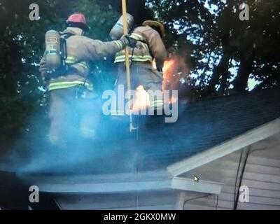 Die Feuerwehrmänner der Vermont Air National Guard arbeiten in den frühen Morgenstunden des Mittwoch, 14. Juli 2021, daran, einen Brand auf dem Dach eines kleinen Mehrfamilienhauses in Winooski, VT, zu löschen. Stockfoto