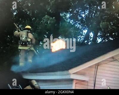 Die Feuerwehrmänner der Vermont Air National Guard arbeiten in den frühen Morgenstunden des Mittwoch, 14. Juli 2021, daran, einen Brand auf dem Dach eines kleinen Mehrfamilienhauses in Winooski, VT, zu löschen. Stockfoto