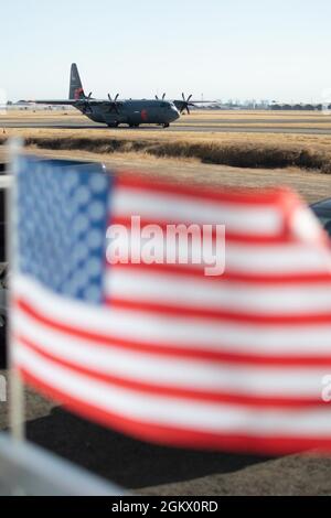 Eine California Air National Guard C-130 nimmt am 14. Juli 2021 an der CAL FIRE Air Tanker Base, McClellan Park, Kalifornien, ein Taxi zur Start- und Landebahn, während die US-Flagge im Wind winkt. Die mit der Air Force C-130 MAFFS ausgerüsteten Flugzeuge von Channel Islands, Kalifornien, wurden vom National Interagency Fire Center angefordert und vom Verteidigungsminister genehmigt und bieten einzigartige Löschkapazitäten. Die MAFFS-Teams der Air Force werden von der 153. Air Expeditionary Group der First Air Force (Air Forces Northern) verwaltet. Stockfoto