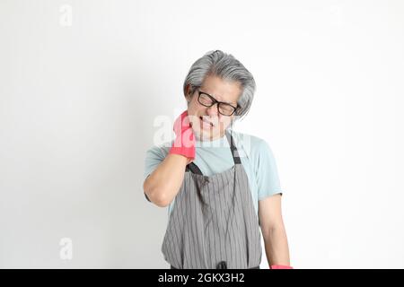 Die ältere asiatische Haushälterin, die auf weißem Hintergrund steht. Stockfoto