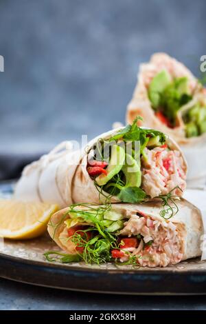 Frische und gesund verpackte Tortilla mit Krabbensalat, Gurke, Avocado, Pfeffer und grünen Kräutern Stockfoto