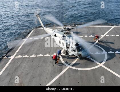 210715-N-OH262-0057 ATLANTIK (15. JULI 2021)-- Mariners des Zivildienstes, die an den Flottennachfüllungsöler des Militärischen Sealift-Kommandos USNS Joshua Humphreys (T-AO 188) angeschlossen sind, laufen zu einem HS-60-Hubschrauber, der dem Helicopter Sea Combat Squadron 22 (HSC 22) zugewiesen wurde, um das Flugzeug zu sichern, nachdem es am 15. Juli an Bord des Schiffes gelandet war, während es auf See im Atlantik war. Stockfoto