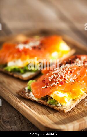 Gesalzener Lachs, Rührei, Avocado und Frischkäse Roggen-Toast Stockfoto