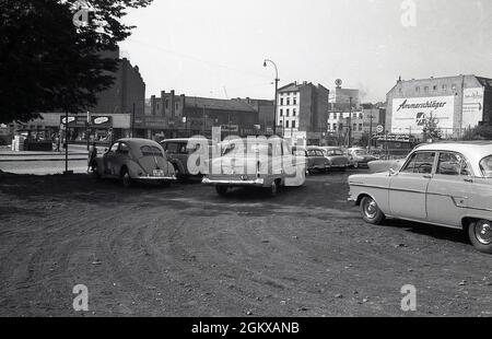 60er Jahre, historischer, gebrauchter oder gebrauchter Parkplatz, mit Autos der damaligen Zeit, die draußen auf einem Schottergebiet in einer Stadt, Deutschland, geparkt wurden. Stockfoto