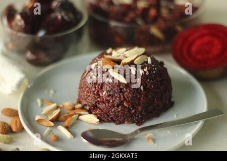 Rote Bete datiert Halwa, eine schnelle Halwa mit ein paar Zutaten. Geriebene Rote Beete, Milch, Zucker, gehackte Datteln, Ghee, Rosinen, garniert mit gehackten Mandeln Stockfoto