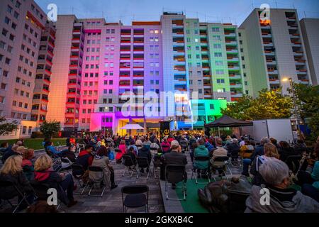 Bremen, Deutschland. September 2021. Beim Open-Air-Konzert „Singing Balconies“ musizierten Sänger aus Bremen und Umgebung im Innenhof einer Wohnanlage und auf einem Balkon. Die Zuschauer konnten auf Sofas, Stühlen und Bänken Platz nehmen, um der Musik zuzuhören, die Bewohner konnten auch von ihren Balkonen aus zusehen. Quelle: Sina Schuldt/dpa/Alamy Live News Stockfoto