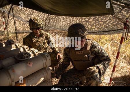 Ein Mitglied der Australian Defence Force und des U.S. Marine Corps PFC. Albert Haynes (rechts), ein Feldartilleriekanonier mit Golfbatterie, 2d-Bataillon, 11. Marine, derzeit an die 31. Marine Expeditionary Unit angeschlossen, Standby, um während der Übung eine Feuermission durchzuführen Talisman Sabre 21 im Shoalwater Bay Training Area, Queensland, Australien, 17. Juli 2021. Australische und US-Streitkräfte vereinen sich alle zwei Jahre für Talisman Sabre, eine einmonatige Multi-Domain-Übung, die die Fähigkeiten von Alliierten und Partnern stärkt, um auf das gesamte Spektrum der Indo-Pacific-Sicherheitskonzerte zu reagieren. Haynes stammt aus Emporiu Stockfoto