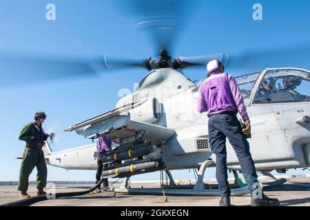 210718-N-XB010-1023 KORALLENMEER (18. Juli 2021) Seeleute, die der USS New Orleans (LPD 18) und Marines, die an die 31. Marine Expeditionary Unit (MEU) angeschlossen sind, zugewiesen wurden, tanken auf dem Flugdeck einen Hubschrauber des US Marine Corps AH-1Z Cobra auf. New Orleans, Teil der America Expeditionary Strike Group, arbeitet zusammen mit der 31. MEU im Verantwortungsbereich der 7. US-Flotte, um die Interoperabilität mit Verbündeten und Partnern zu verbessern und als einsatzbereite Einsatztruppe für Frieden und Stabilität in der Indo-Pazifik-Region zu dienen. Stockfoto