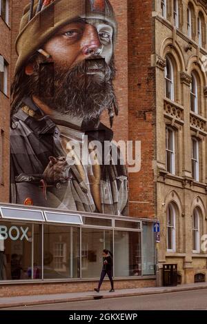 Ein erstaunliches Wandgemälde des Künstlers, das an der Wand des Leicester Creative Business Depot angebracht ist, ragt weit über einem Passanten auf. Stockfoto