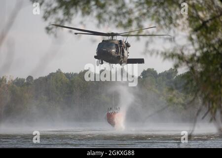 Soldaten der Nationalgarde der Kentucky Army sammeln Wasser, während sie am 19. Juli 2021 im Wendhell H. Ford Regional Training Center in Greenville, KY, Wassereimer trainieren. Besatzungsmitglieder von Bravo Co., 2/147. Assault Helicopter Battalion Züge mit UH-60 Black Hawks, um Waldbrände und Waldbrände zu löschen, um lokale Feuerwehren in Kentucky und den Nachbarstaaten zu unterstützen. Dieses Bild wurde elektronisch beschnitten und ethisch verbessert, um das Motiv hervorzuheben, und stellt das Motiv oder das Originalbild in keiner Weise falsch dar Stockfoto