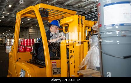 210719-N-PG226-1275 ATLANTISCHER OZEAN (19. Juli 2021) Flugzeugtechniker 3. Klasse Tristan Thomas-Gomez aus Los Angeles bewegt mit einem Gabelstapler Farbfässer in der Hangarbucht des Flugzeugträgers USS Harry S. Truman (CVN 75) der Nimitz-Klasse. Truman führt im Atlantischen Ozean Bereitschaftstrainings durch, um sich auf den zukünftigen Betrieb vorzubereiten. Stockfoto