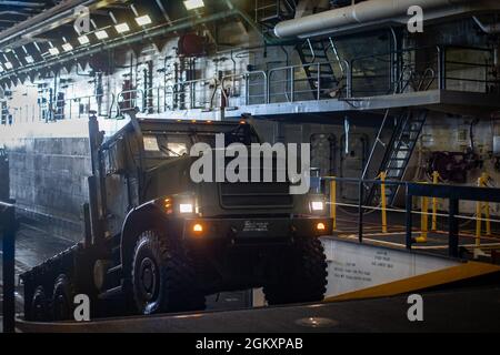 Das US Marine Corps fährt auf die USS Arlington (LPD-24) mit einem mittleren taktischen Fahrzeug, das während der Proben der Mission Defence Support of Civil Authorities (DSCA) auf dem Marinestützpunkt Norfolk, Virginia, am 21. Juli 2021 eingesetzt wird. Marineinfanteristen und Matrosen mit der II Marine Expeditionary Force Maritime DSCA Task Force, die vom Combat Logistics Bataillon 22 kommandiert wurde, und Matrosen an Bord der USS Arlington führten eine Probeverladung für zerstörerische Wettermissionen durch, um sich auf eine zukünftige DSCA-Mission während der Hurrikansaison 2021 vorzubereiten und zu Proben. Stockfoto