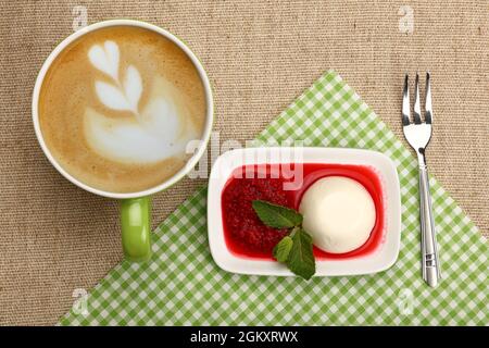 Nahaufnahme serviert Panna Cotta traditionelles italienisches Dessert mit Himbeermarmelade und Tasse Cappuccino-Kaffee, erhöhte Ansicht von oben, direkt darüber Stockfoto