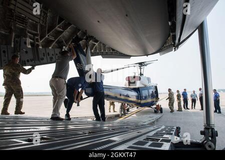 Flieger der 167. Einsatzgruppe und Helikopter-Betreuer von Amentum nutzen ein Windensystem, um einen UH-1N Huey-Hubschrauber vom 1. Helicopter Squadron auf ein C-17 Globemaster III-Flugzeug mit dem 167. Airlift Wing während eines Hubschrauberladetrainings auf der Fluglinie am Joint Base Andrews zu laden, Maryland, 21. Juli 2021. Das Training verbesserte die Effizienz und Effektivität des Ladens und Transportes dieser Hubschraubertypen. Stockfoto