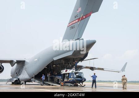 Luftwaffe mit der 167. Operations Group und Helikopter-Betreuer mit Amentum entlasten einen UH-1N Huey-Hubschrauber aus dem 1. Helicopter Squadron aus einem C-17 Globemaster III-Flugzeug mit dem 167. Airlift Wing am Ende eines Hubschrauberladertrainings auf der Fluglinie bei Joint Base Andrews, Maryland, 21. Juli 2021. Das Training verbesserte die Effizienz und Effektivität des Ladens und Transportes dieser Hubschraubertypen. Stockfoto